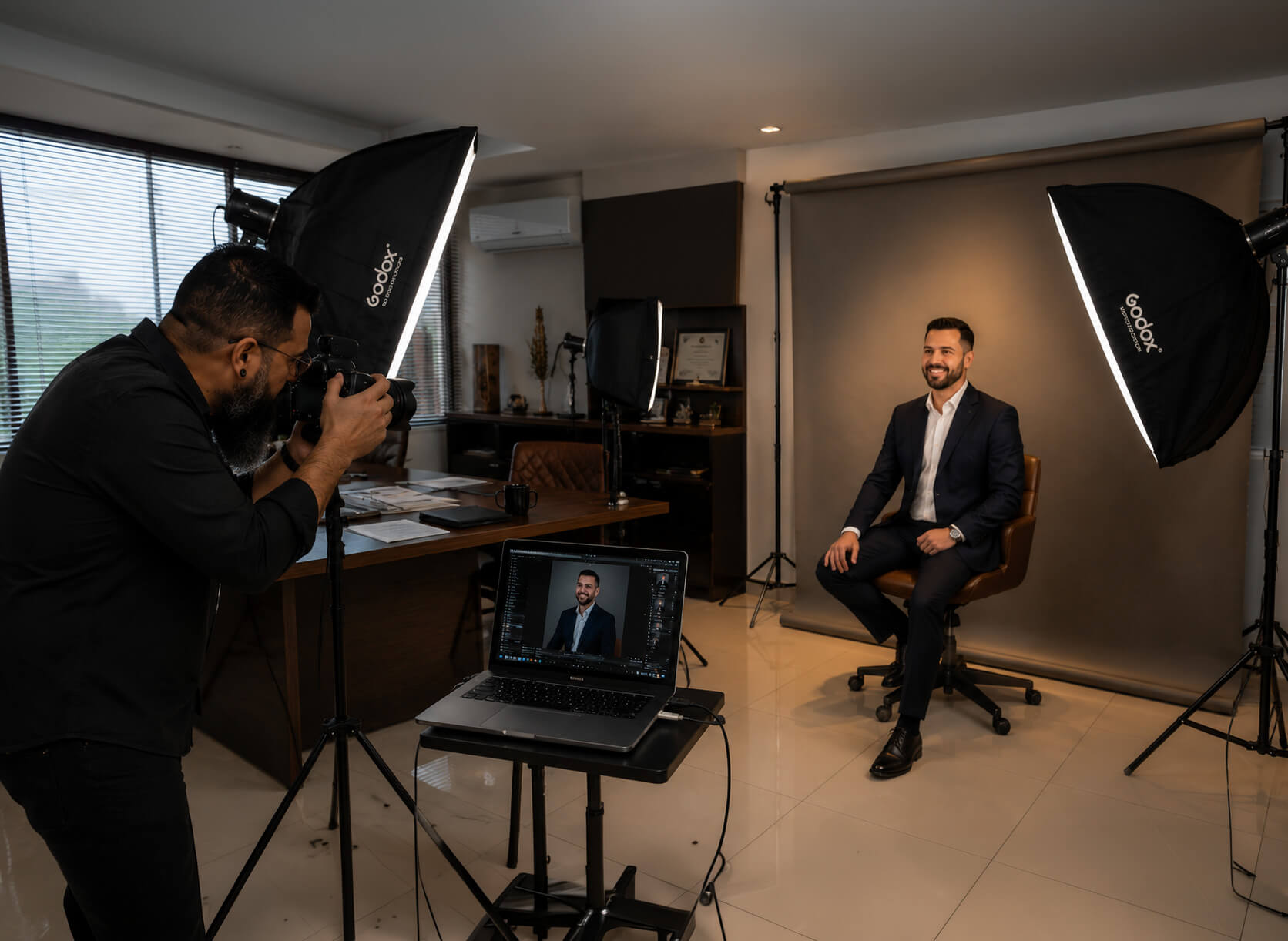 Adriano de Azeredo fotografando um cliente com estrutura de iluminação montada no ambiente de trabalho