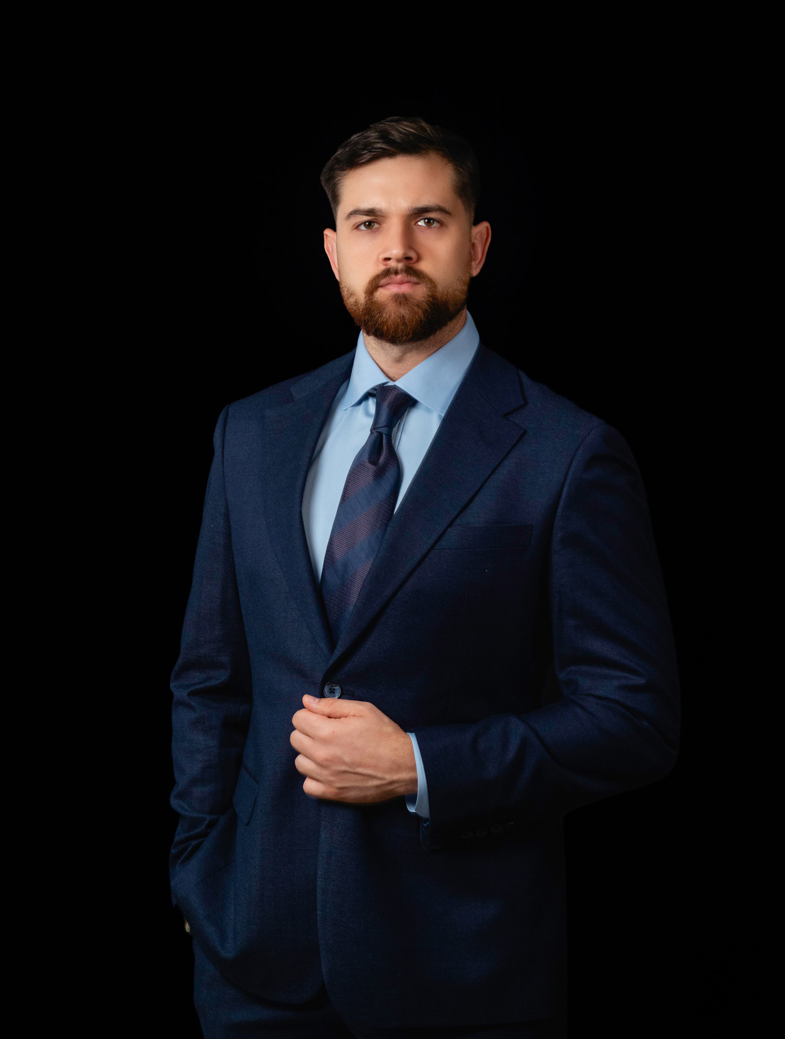 Homem de terno azul em retrato profissional sobre fundo preto